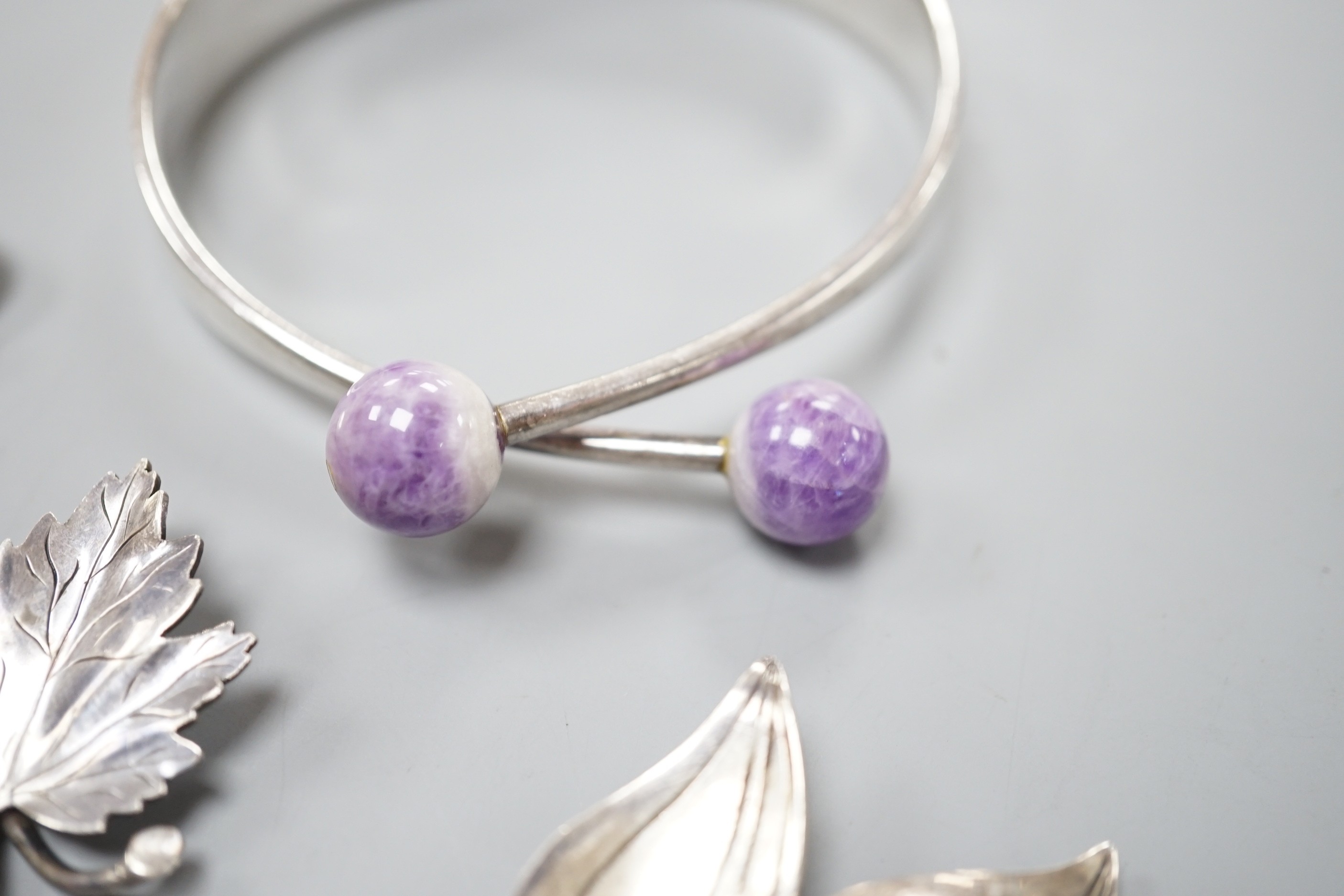 Four items of 20th century Scandinavian white metal jewellery, including a brooch and amethyst quartz set bangle by Hans Hansen and two Swedish white metal leaf brooches, bangle interior diameter 62mm.